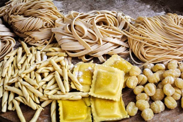 Spaghetti, tagliatelles, fettuccine, linguine, ravioli sur une vieille table en bois.
